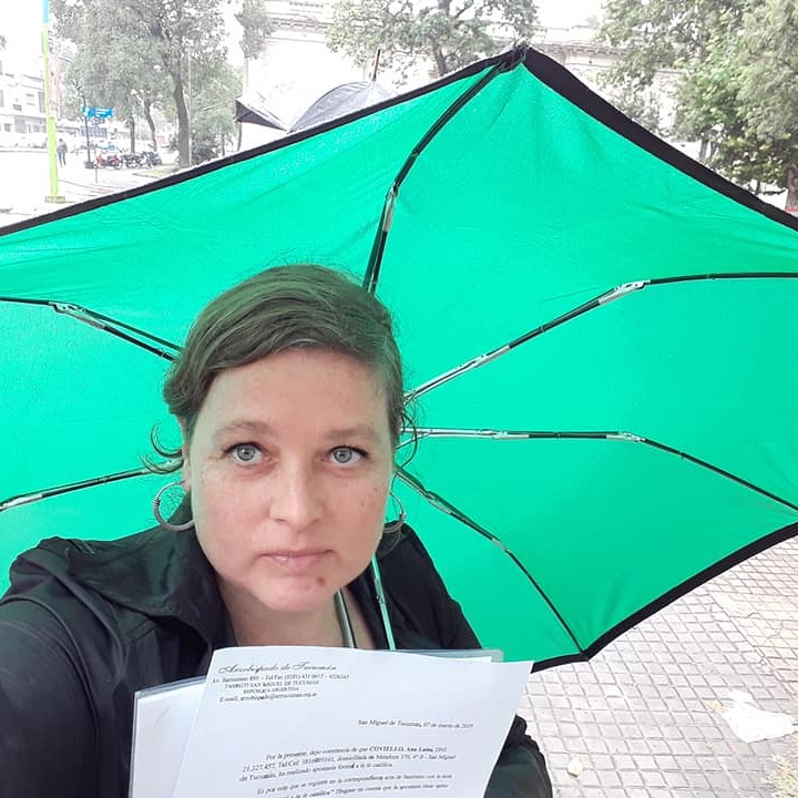 Retrato de Ana Luisa Coviello sosteniendo un paraguas verde, sonriendo levemente a cámara